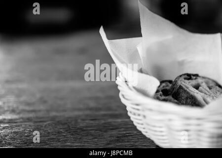 Brotscheiben in den Korb mit unscharfen Holztisch Hintergrund. Schwarz und weiß. Stockfoto