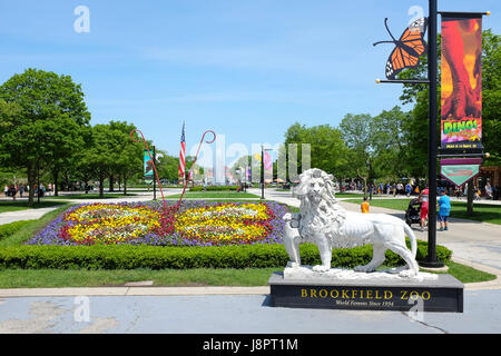 BROOKFIELD, ILLINOIS - 27. Mai 2017: Löwenstatue am Südtor Brookfield Zoo. Roosevelt-Brunnen und das Karussell sind im Hintergrund Stockfoto