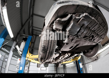 Auto-Ansicht von unten. Vorderwagen Federung. die Garage Mechaniker das Auto auf der Hebebühne angehoben Stockfoto