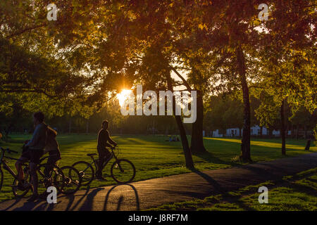 Jugendliche auf dem Fahrrad in einem Londoner Park wie die Sonne untergeht Stockfoto