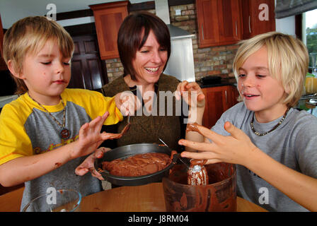 Jenny Lewis Kochen in ihrem Haus in Eastington, in der Nähe von Stroud, Gloucestershire, mit Söhnen Ollie (6), gelbes Hemd und Josh (12) Stockfoto