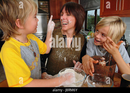 Jenny Lewis Kochen in ihrem Haus in Eastington, in der Nähe von Stroud, Gloucestershire, mit Söhnen Ollie (6), gelbes Hemd und Josh (12) Stockfoto