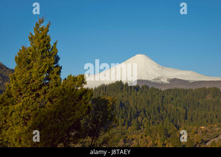 Schneebedeckte Gipfel der Antuco Vulkan (2.979 m) erhebt sich über einem bewaldeten Tal im Laguna de Laja Nationalpark in der Region Bio Bio Chile. Stockfoto