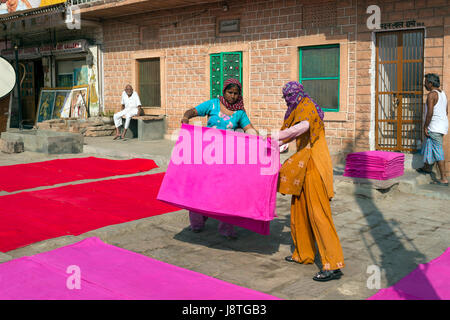 Frauen, die Faltung des gefärbten Stoffes auf einem Bürgersteig in Jodhpur, Indien Stockfoto