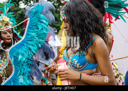 Eine junge Frau, die Teilnahme an der Lesung Karneval hält um ihr Handy zu überprüfen, Stockfoto