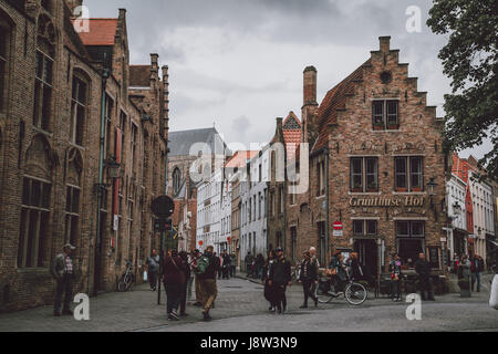 Eine gepflasterte Straße gesäumt von Stein und roten Ziegel Häuser in Brügge (Brygge), Belgien, an einem bewölkten Frühlingstag. Stockfoto