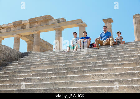 LINDOS, Rhodos, Griechenland - 3. September 2015: Touristen ruht auf einer Treppe in der Nähe der Kolonnade des Grand hellenistische Säulenhalle des alten Acrop Stockfoto