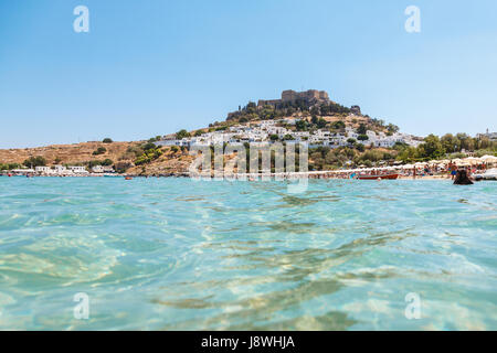 Blick auf Dorf Lindos und Ruinen mit Akropolis auf einem Hügel aus dem Wasser in Lindos, Rhodos, Dodekanes, Griechenland Stockfoto