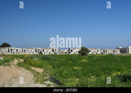 Menge von leeren Elementen neu gebauten Häuser im Hintergrund und ein blauer Himmel außerhalb des Dorfes Lapta im Norden Zyperns. Stockfoto