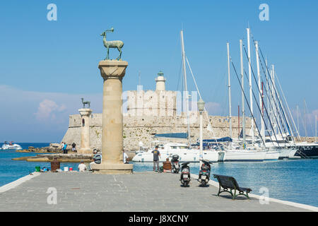 Rhodos, Griechenland - 13. Juni 2015: Menschen im Mandraki Hafen Hafen beobachten Rehe, Statuen und Fort St. Nikolaus mit dem Leuchtturm in Rhodos, Griechenland Stockfoto