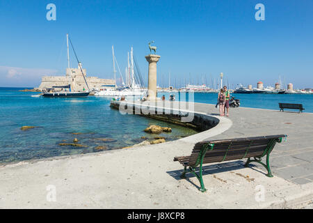 Rhodos, Griechenland - 13. Juni 2015: Menschen im Mandraki Hafen Hafen beobachten Rehe, Statuen und Fort St. Nikolaus mit dem Leuchtturm in Rhodos, Griechenland Stockfoto