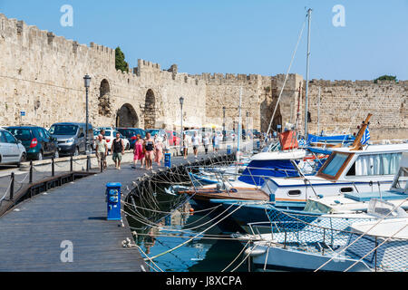 Rhodos, Griechenland - 20. August 2015: Menschen Sporttreibende auf einem hölzernen Damm der Mauern der Altstadt und ein Dock mit Reise- und Fischer Boote zu beobachten. Stockfoto