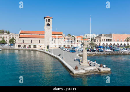 Rhodos, Griechenland - 12. Juni 2015: Aussicht auf eine Mandaki Hafen Hafen und einem Damm mit einer Kapelle und die Statue des Hirsches. Menschen zu Fuß auf einem Damm beobachten Stockfoto