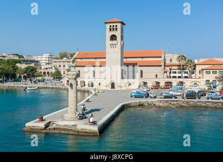 Rhodos, Griechenland - 12. Juni 2015: Blick auf eine Mandaki Hafen Port und Kapelle. Menschen zu Fuß auf einem Damm beobachten Rehe, Statuen und Fort St. Nikolaus Stockfoto