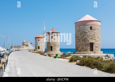 Rhodos, Griechenland - 20. August 2015: Passanten in einem Hafen in der Nähe von Windmühlen und Fort von St. Nikolaus in der Stadt Rhodos, Griechenland Stockfoto