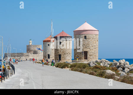 Rhodos, Griechenland - 20. August 2015: Passanten in einem Hafen in der Nähe von Windmühlen und Fort von St. Nikolaus in der Stadt Rhodos, Griechenland Stockfoto