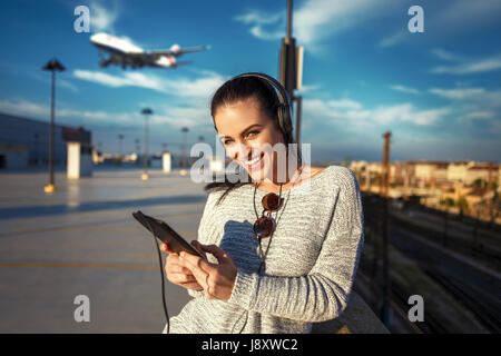 Junge Frau, die Bestellung von Flugtickets per Tablet am Flughafen Stockfoto