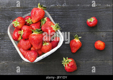 Volle Schüssel rote frische Erdbeeren in einem dunklen Holz Hintergrund Stockfoto
