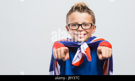 Lustig Lächeln Superhelden junge zeigt auf Kamera, trägt ein Union Jack-Flagge als Umhang er Stockfoto