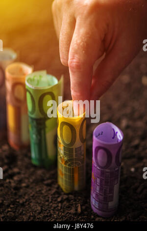 Euro Geld, landwirtschaftliche Konzeptbild mit der Hand pflücken EU Geldschein aus fruchtbarem Boden Boden ernten Stockfoto