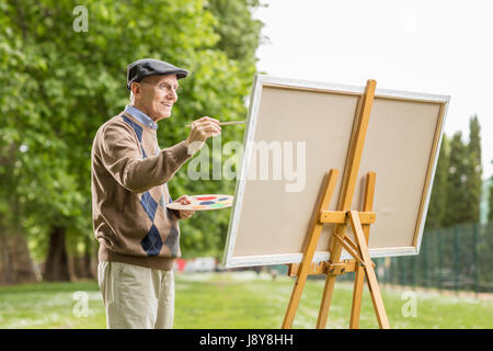 Älterer Mann Gemälde auf einer Leinwand im park Stockfoto