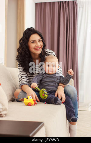 junge Mutter und ihr Sohn zu spielen und Lesen eines Buches auf Sofa, Lebensstil Stockfoto