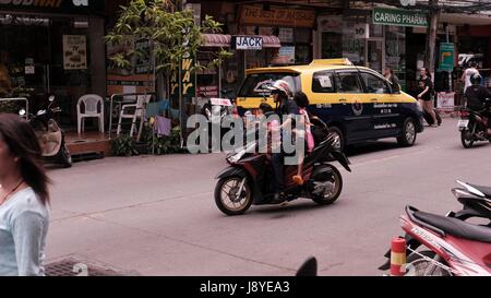 Dame mit zwei Kindern auf einem Motorrad im Straßenverkehr Soi Buakhao und Soi Diana Pattaya Thailand die meisten gefährlichen Kreuzung an einem düsteren bewölkten Tag Stockfoto