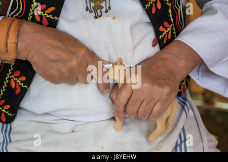 Holzschnitzer in Tracht gekleidet schnitzt aus Holz - Volkskunst Stockfoto
