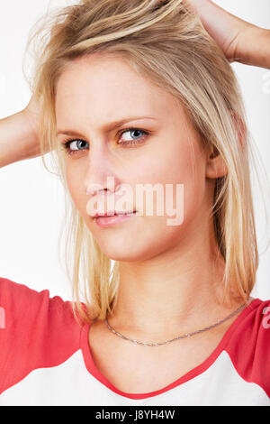 junge blonde Frau mit Händen in Haar Stockfoto