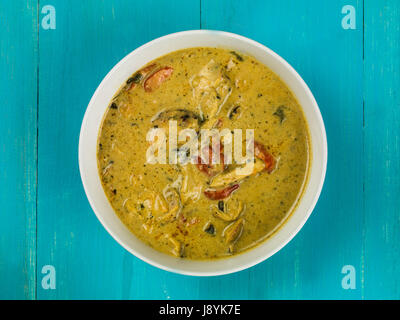 Schüssel mit Panang Thai Huhn mit gebratenem Gemüse auf blauem Grund Stockfoto