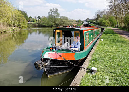 Männlich, eine Dose Bier auf der Vorderseite ein Narrowboat bei sonnigem Wetter genießen Stockfoto