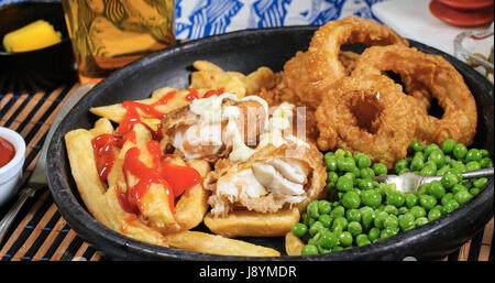 Blick auf eine englische Fish &amp; Chips mit Erbsen, Ring Zwiebeln und Sauce tartar Stockfoto