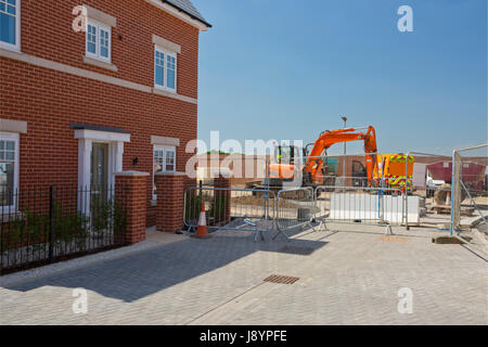 Ein neues Haus in eine Greenfield-Wohnsiedlung mit Bauarbeiten weiterhin neben Stockfoto
