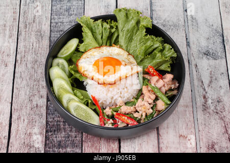 Beliebte thailändische, Jasminreis gekrönt rühren - würziger Basilikum mit Garnelen, Tintenfisch und knusprige Hähnchen gebraten und gebratenem Ei Anruf Kao Pad Kra Prao Kai. Stockfoto