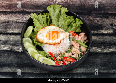 Beliebte thailändische, Jasminreis gekrönt rühren - würziger Basilikum mit Garnelen, Tintenfisch und knusprige Hähnchen gebraten und gebratenem Ei Anruf Kao Pad Kra Prao Kai. Stockfoto