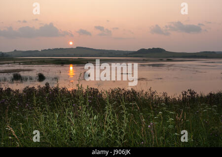 Schönen Sommer Sonnenuntergang über Teich und kleinen Dorf hinter ihm. Stockfoto