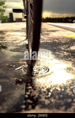 3D-Rendering Fahrradreifen auf Pfütze vor unscharfen Asphalt stehen und am Abend Sonnenschein Stockfoto