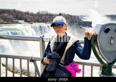 Mädchen mit Sonnenbrille mit Kamera an den Niagarafällen von der amerikanischen Seite, USA. Stockfoto