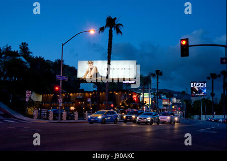 Eine Mode-Werbetafel beleuchtet in der Abenddämmerung über Verkehr auf dem Sunset Strip im Stadtteil West Hollywood in Los Angeles, CA Stockfoto