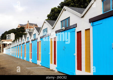 Strandhütten/Segeln Hütten Waterfront, Oriental Parade Wellington, Neuseeland, mit Kloster im Hintergrund. Stockfoto