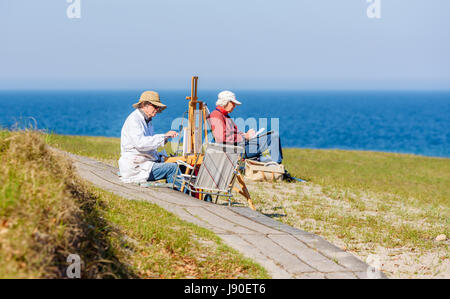 Havang, Schweden - 18. Mai 2017: Dokumentation des Alltags im Havang Naturreservat. Ältere Künstler malen und zeichnen am Meer auf einem sonnigen lösen Stockfoto