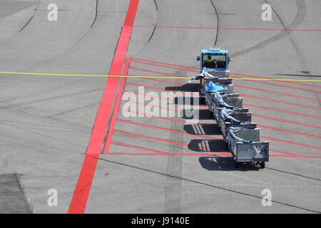 Flughafen-Schürze mit Gepäckwagen Stockfoto