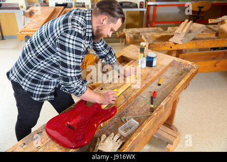 Handwerker, die Schleifen einen Gitarrenhals aus Holz in Werkstatt Stockfoto