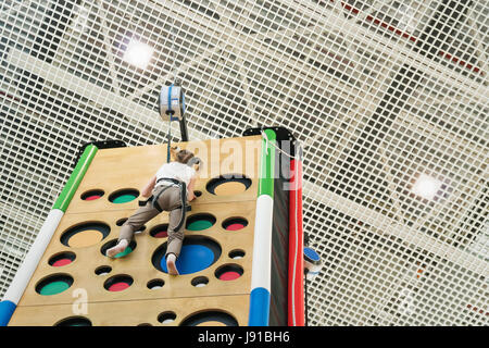 Teenager Mädchen kletterte an die Spitze an der Kletterwand, Nahaufnahme Stockfoto