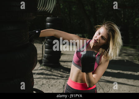 Zuversichtlich Mädchen Training Boxe in einem offenen öffentlichen Fitnessstudio, dramatisches Licht mit viel Kontrast, das Modell zu betonen Stockfoto