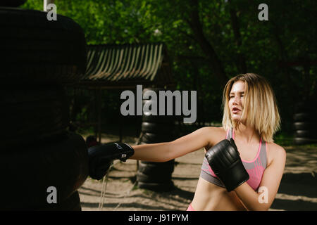 Zuversichtlich Mädchen Training Boxe in einem offenen öffentlichen Fitnessstudio, dramatisches Licht mit viel Kontrast, das Modell zu betonen Stockfoto