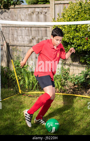 Junge Praktiken Fußball in einen englischen Garten Stockfoto