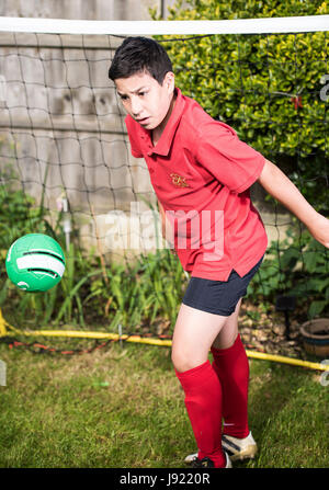 Junge Praktiken Fußball in einen englischen Garten Stockfoto