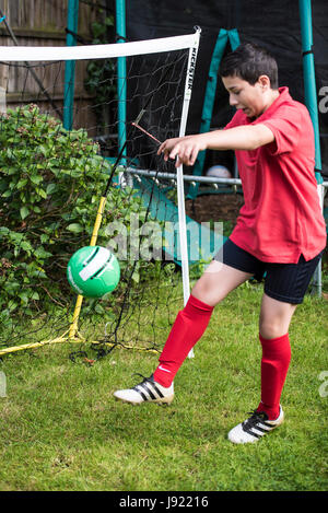 Junge Praktiken Fußball in einen englischen Garten Stockfoto