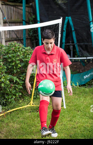 Junge Praktiken Fußball in einen englischen Garten Stockfoto